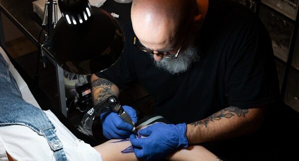 Mejores tatuadores - Tatuador reconocido como uno de los mejores tatuadores en Sevilla realizando un tatuaje en el brazo de una mujer