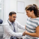 Proctólogos - Médico proctólogo reconocido como uno de los mejores proctólogos de Sevilla evaluando a una mujer en consulta de proctología por problemas en el colon