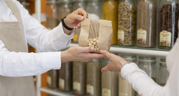 en unas de las tiendas a granel, un vendedor le da un producto en una bolsa biodegradable