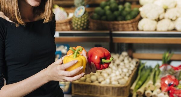 en una de las tiendas de alimentos saludables, una mujer revisa dos pimentones