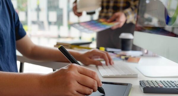 Cursos de diseño gráfico un chico de camisa azul dibuja en una tableta gráfica