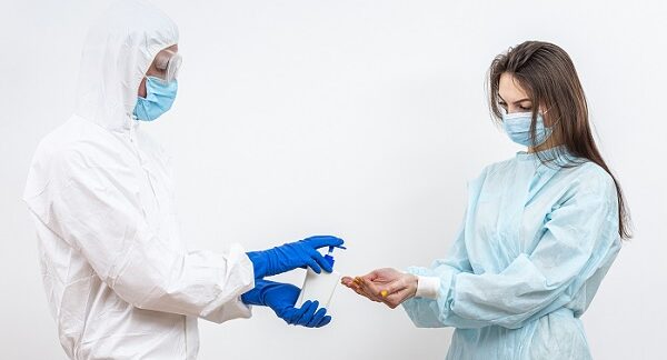 uno de los especialistas en enfermedades infecciosas, le echa desinfectante en las manos a paciente femenina