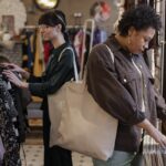 de las tiendas de ropa vintage, dos mujeres revisan prendas en una tienda vintage