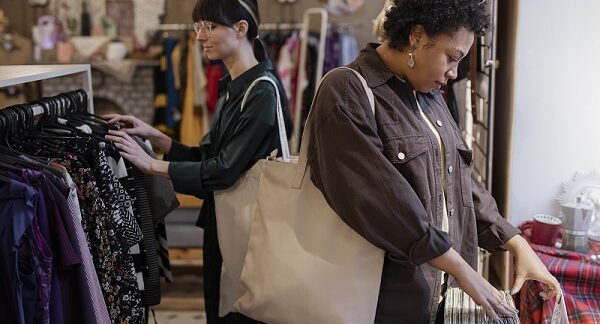de las tiendas de ropa vintage, dos mujeres revisan prendas en una tienda vintage