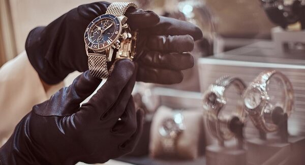 tiendas de relojes - un relojero con guantes exhibe un reloj lujoso