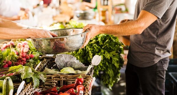 mejores mercados gastronómicos - una persona compra hortalizas en un puesto de mercado