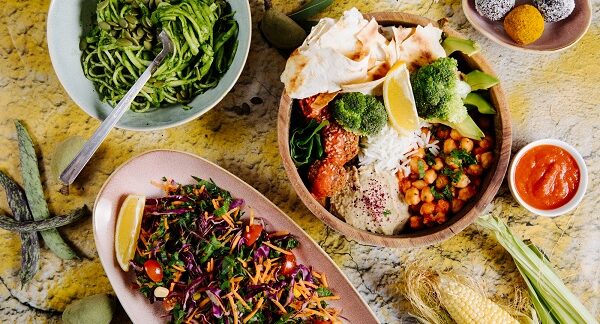 mejores restaurantes vegetarianos - algunos platos vegetarianos como: Espagueti, ensalada de verduras y plato principal, con verduras y galletas, dispuestos en una mesa